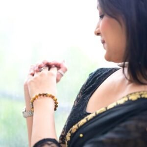 Elegant woman in a black saree wearing a Tiger Eye crystal bracelet, symbolizing confidence and inner strength.
