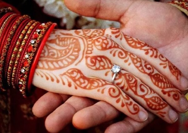 Bride’s mehndi hand with engagement ring held by groom — symbol of love and destiny in marriage numerology, Bhopal.